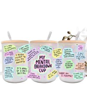 May include: Set of three white ceramic mugs with a wooden lid and a straw. Each mug has a different design with colorful text and illustrations. The text on the mugs includes phrases like "My Mental Breakdown Cup", "It's okay to have low energy days", and "I allow myself to feel my anxiety".