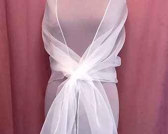 May include: White sheer shawl with a delicate, flowing drape. The shawl is tied at the waist and has a long, flowing train.