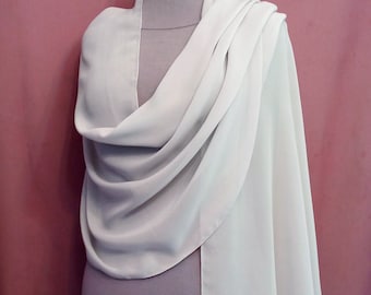 Puede incluir: Un chal de gasa blanco drapeado sobre un maniquí. El chal es largo y fluido, con un diseño sencillo.