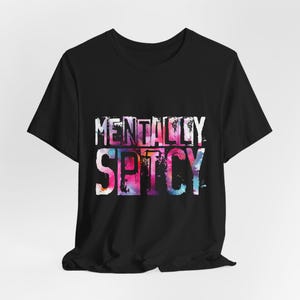 Puede incluir: Camiseta negra con la frase "MENTALLY SPICY" en un dise&ntilde;o colorido estilo acuarela. El texto est&aacute; en una fuente desgastada, a&ntilde;adiendo un toque &uacute;nico a la camiseta gr&aacute;fica.