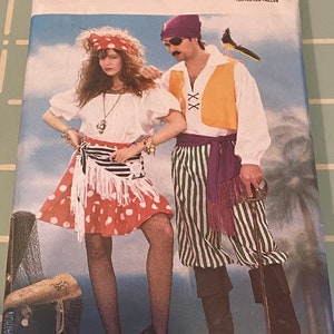 May include: A vintage sewing pattern for a pirate costume. The pattern is for a woman's and a man's costume. The woman's costume includes a white blouse with a red and white polka dot skirt, a black belt with a fringe, and a red and white bandana. The man's costume includes a white shirt with a yellow vest, a purple bandana, and striped pants. The pattern number is 6731. The text on the pattern says "All sizes included, Toutes les tailles".