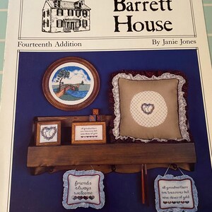 May include: A cross-stitch pattern booklet for a house with the title "Barrett House, Fourteenth Addition" by Janie Jones. The cover features a drawing of a house, a cross-stitch design of a bridge, and three cross-stitch designs with sayings about friends and grandmothers.