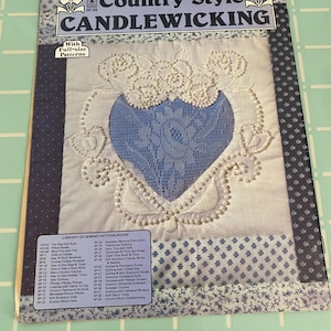 May include: A vintage sewing pattern book titled "Country Style Candlewicking." The cover features a blue heart design with white embroidery and the text "With Full-size Patterns." The book includes a list of sewing pattern books.