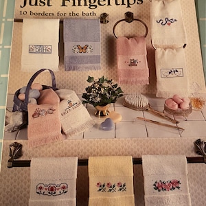 May include: A book cover with the title "Just Fingertips" and the subtitle "10 borders for the bath". The cover features a variety of embroidered towels with different designs, including butterflies, flowers, and bath-themed motifs.