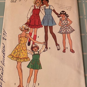 May include: A sewing pattern for children's dresses. The pattern is for sizes 6-77 and includes four different styles. The pattern is from Simplicity and the pattern number is 6996.