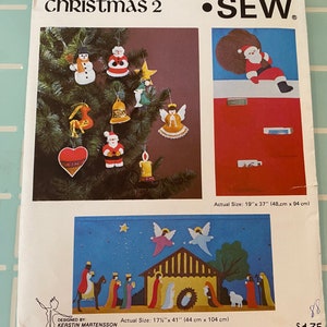 May include: A Kwik Sew pattern for Christmas decorations and a nativity scene. The pattern includes instructions for making a snowman, a bell, a star, an angel, a Santa Claus, a heart, a candle, and a nativity scene with a stable, a star, angels, a sheep, and three wise men. The pattern is 48 cm by 94 cm.