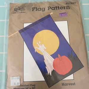 May include: A flag pattern for a harvest themed flag. The pattern features a corn stalk, a pumpkin, and a full moon on a blue background. The finished flag measures 34 inches by 50 inches. The pattern is made in the USA.