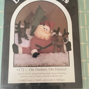 May include: A Christmas sewing pattern for a 10-inch beanbag Santa, two floppy beanbag reindeer, and a 12-inch fabric-covered cardboard tree. The pattern is titled "#173 - On Dasher, On Dancer" and is copyrighted 1992 by Nancy J. Smith and Lynda S. Milligan.