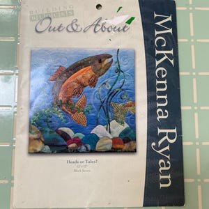 May include: A McKenna Ryan Building Blocks Out & About quilt pattern titled Heads or Tales? Block Seven. The packaging features a 12" x 12" square illustration of a fish swimming underwater among colorful rocks and green aquatic plants on a blue background.