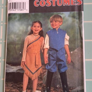 May include: A Simplicity Costumes sewing pattern envelope featuring two children wearing outfits labeled A and B. Outfit A is a tan fringed dress with blue trim. Outfit B is a blue vest and pants set with a white shirt and black boots. The text includes 9722, sizes 3, 4, 5, 6, 7, 8, and a barcode.