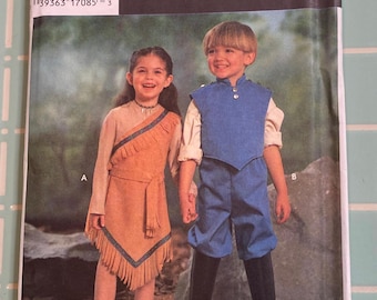 May include: A Simplicity Costumes sewing pattern envelope featuring two children wearing outfits labeled A and B. Outfit A is a tan fringed dress with blue trim. Outfit B is a blue vest and pants set with a white shirt and black boots. The text includes 9722, sizes 3, 4, 5, 6, 7, 8, and a barcode.