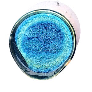 May include: A handmade, oval-shaped ceramic dish with a vibrant blue and turquoise interior. The dish has a textured surface and a dark, glossy rim. The design resembles an abstract underwater scene, perfect for serving small portions or as a decorative piece.