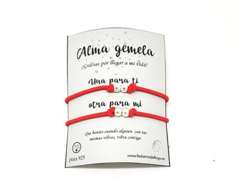 Op de afbeelding: Twee rode armbandjes van touw met zilveren kralen. De kaart staat "Alma gemela! Gracias por llegar a mi vida! Una para ti otra para mi. Que bonito cuando alguien con tus mismas vibras, vibra contigo. Plata 925 www.ladanadellago.es"