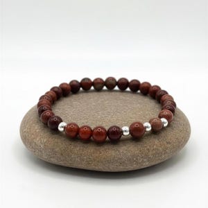 Bracciale elastico in minerale da 6 mm nei toni dell'oro e del rubino, raffigurante l'arcangelo Uriel, simbolo di prosperità.