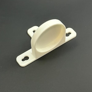 Puede incluir: Soporte de plástico blanquecino con un soporte curvo y dos orificios de montaje. El soporte está diseñado para sujetar un objeto cilíndrico. El diseño es simple y funcional, con una estética limpia y moderna.