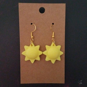 May include: A pair of yellow sun-shaped dangle earrings with gold-colored hooks.