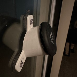 May include: White 3D printed suction cup mount with a black round device attached. The device has the text "Eufy" on it.