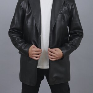 May include: A black leather blazer with a single button closure and a long, fitted silhouette.