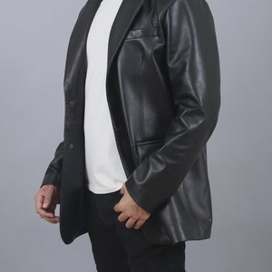 May include: A black leather blazer with a single button fastening and a notched lapel. The blazer has a relaxed fit and a long length.