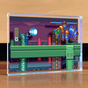 May include: A pixelated image of a video game scene featuring a blue robot character firing a blue energy blast at a flying, orange and blue robot. The scene is set against a backdrop of a city skyline at night.
