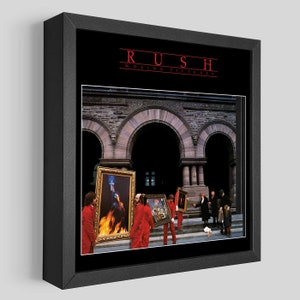 Może przedstawiać: Okładka albumu w ramie dla albumu "Moving Pictures" zespołu Rush. Okładka przedstawia grupę mężczyzn w czerwonych garniturach niosących obrazy w ramach przed kamiennym budynkiem z łukowymi wejściami.