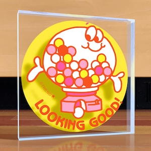 May include: A yellow and orange acrylic plaque with a cartoon gumball machine with the text "Looking Good!" and "OTrend*" on it.