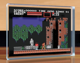 May include: A retro video game screen print featuring a pixelated character in a red and orange suit standing in front of a brick wall. The screen displays the text "SCORE-00000 TIME 0290 STAGE 01 PLAYER ENEMY P-03".