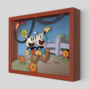 Può includere: Un'opera d'arte incorniciata con due personaggi dei cartoni animati con teste a forma di tazza, sorridenti e che si abbracciano. Lo sfondo include una recinzione, fiori, un sole e un razzo. La cornice è di colore marrone caldo.
