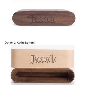 May include: A wooden speaker with the name "Jacob" engraved on the top. The speaker is made of light and dark wood.