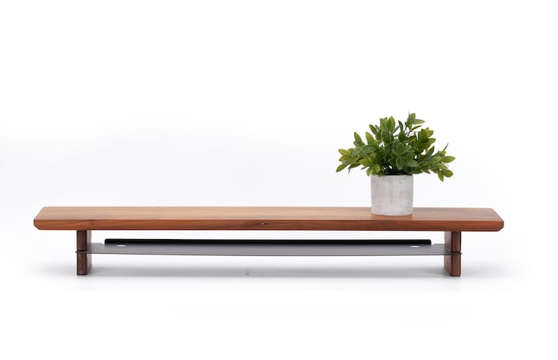May include: A wooden shelf with a metal bar underneath. The shelf is brown and the bar is gray. A small potted plant is on the shelf.