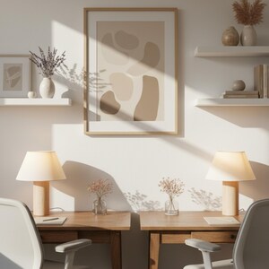May include: A well-lit home office setup featuring two wooden desks with matching chairs. Each desk has a lamp, a small vase of flowers, and a notebook. A framed abstract art piece hangs on the wall, along with floating shelves holding decorative items.