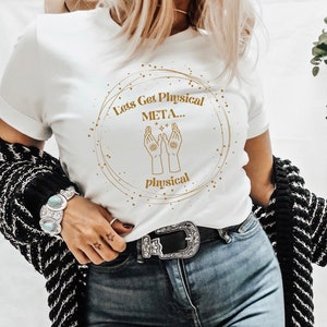 May include: White t-shirt with a gold circle graphic that says "Let's Get Physical META... Physical". The graphic also features two hands with eyes in the palms facing upwards.