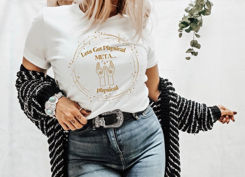 May include: White t-shirt with a gold circle graphic that says "Let's Get Physical META... Physical". The graphic also features two hands with eyes in the palms facing upwards.