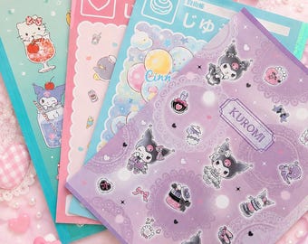 以下が含まれることがあります： サンリオキャラクターが描かれた4冊の長方形のノート。ノートはライトグリーン、ピンク、ブルー、パープルの色合いです。ハローキティ、クロミ、シナモロールのイラストが描かれており、日本語のテキストやハート、風船などのアイコンがデザインされています。