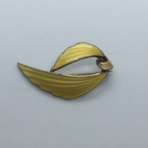 Peut inclure: Une broche en argent sterling et émail jaune en forme d'aile stylisée.