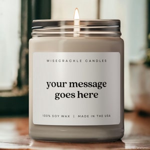 May include: A white candle in a glass jar with a label that says "Wisecrackle Candles" and "your message goes here". The label also says "100% Soy Wax | Made in the USA".