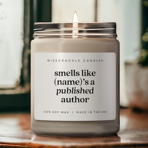 May include: A white candle with a black label that reads "WISECRACKLE CANDLES smells like (name)'s a published author 100% SOY WAX | MADE IN THE USA".