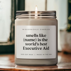以下が含まれることがあります： 「WISECRACKLE CANDLES smells like (name) is the world's best Executive Aid 100% SOY WAX | MADE IN THE USA」と黒のラベルが貼られた白いキャンドルです。