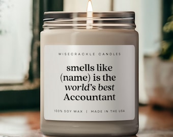May include: A white candle with a black label that reads "WISECRACKLE CANDLES smells like (name) is the world's best Accountant 100% SOY WAX | MADE IN THE USA".