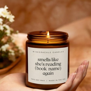 May include: A brown glass candle with a white label that reads "WISECRACKLE CANDLES" and "smells like she's reading (book name) again". The label also says "100% SOY WAX | MADE IN THE USA".