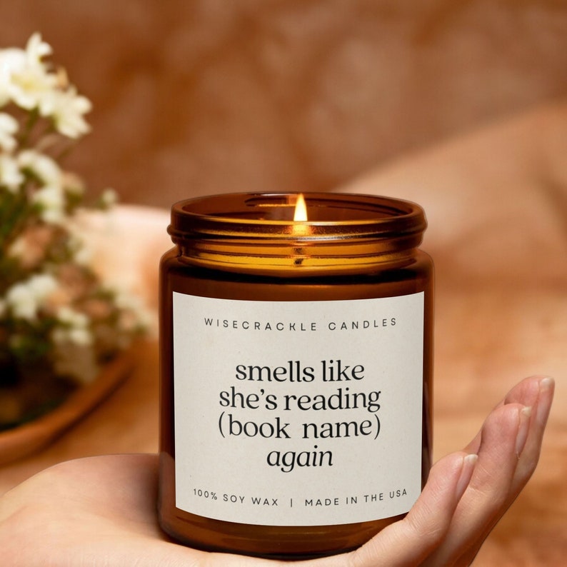 May include: A brown glass candle with a white label that reads "WISECRACKLE CANDLES" and "smells like she's reading (book name) again". The label also says "100% SOY WAX | MADE IN THE USA".