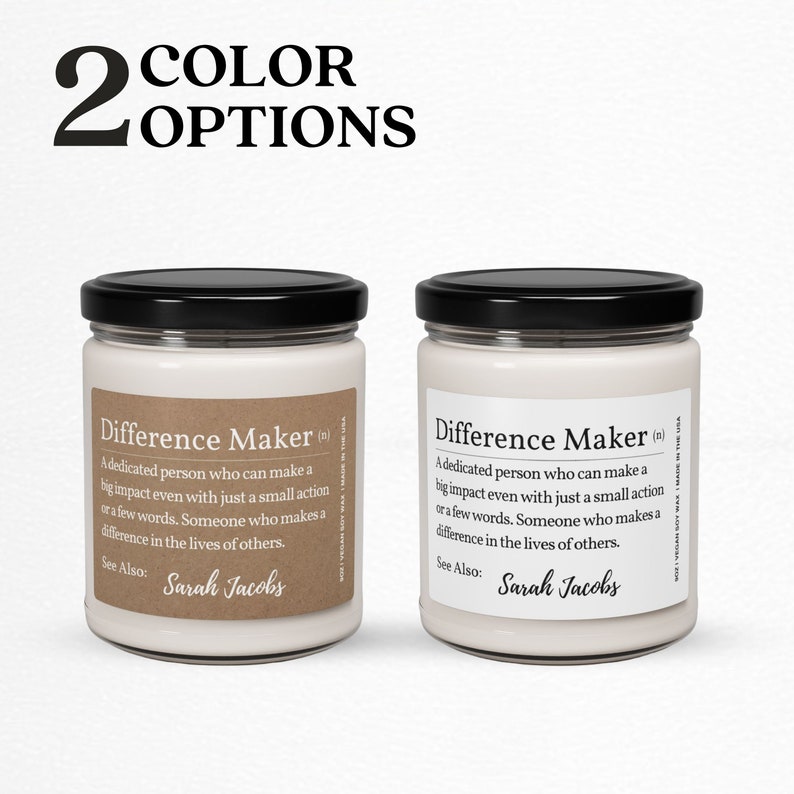 K&ouml;nnte beinhalten: Zwei wei&szlig;e Kerzenbeh&auml;lter mit schwarzen Deckeln. Die Vorderseite jedes Beh&auml;lters hat ein braunes Etikett mit dem Text "Difference Maker (n)" und einer Definition des Wortes. Der Text auf dem Etikett enth&auml;lt auch "Siehe auch: Sarah Jacobs".