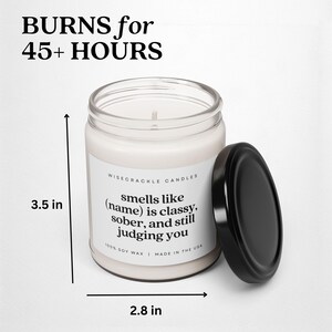 May include: A white candle with a black lid and label that reads "WISECRACKLE CANDLES smells like (name) is classy, sober, and still judging you 100% SOY WAX | MADE IN THE USA". The candle is 3.5 inches tall and 2.8 inches wide.