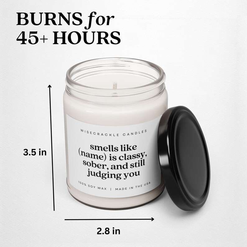 May include: A white candle with a black lid and label that reads "WISECRACKLE CANDLES smells like (name) is classy, sober, and still judging you 100% SOY WAX | MADE IN THE USA". The candle is 3.5 inches tall and 2.8 inches wide.
