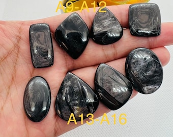 May include: Six black gemstone cabochons with silver streaks, labeled A9-A12 and A13-A16. The stones are displayed on a hand.