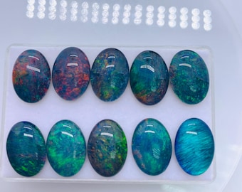 Puede incluir: Una colección de diez ópalos ovalados, cada uno mostrando un patrón único de colores que incluyen verde, azul, rojo y naranja. Los ópalos están colocados en un recipiente de plástico transparente, mostrando sus superficies pulidas y variaciones de color internas.