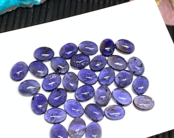 May include: A collection of 25 oval-shaped, purple amethyst gemstones. The stones are smooth and polished, with a slight shimmer.