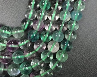 May include: A strand of green, blue, and purple fluorite beads. The beads are round and have a smooth, polished finish.
