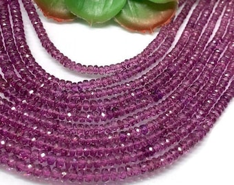 May include: A strand of purple faceted gemstone beads. The beads are small and round, and they are strung on a clear thread. The beads are arranged in a loose, flowing pattern.