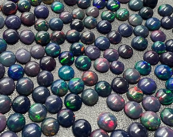 May include: A large collection of black opal cabochons, each with a unique iridescent sheen. The opals are round and smooth, with a variety of colours including green, blue, and red.